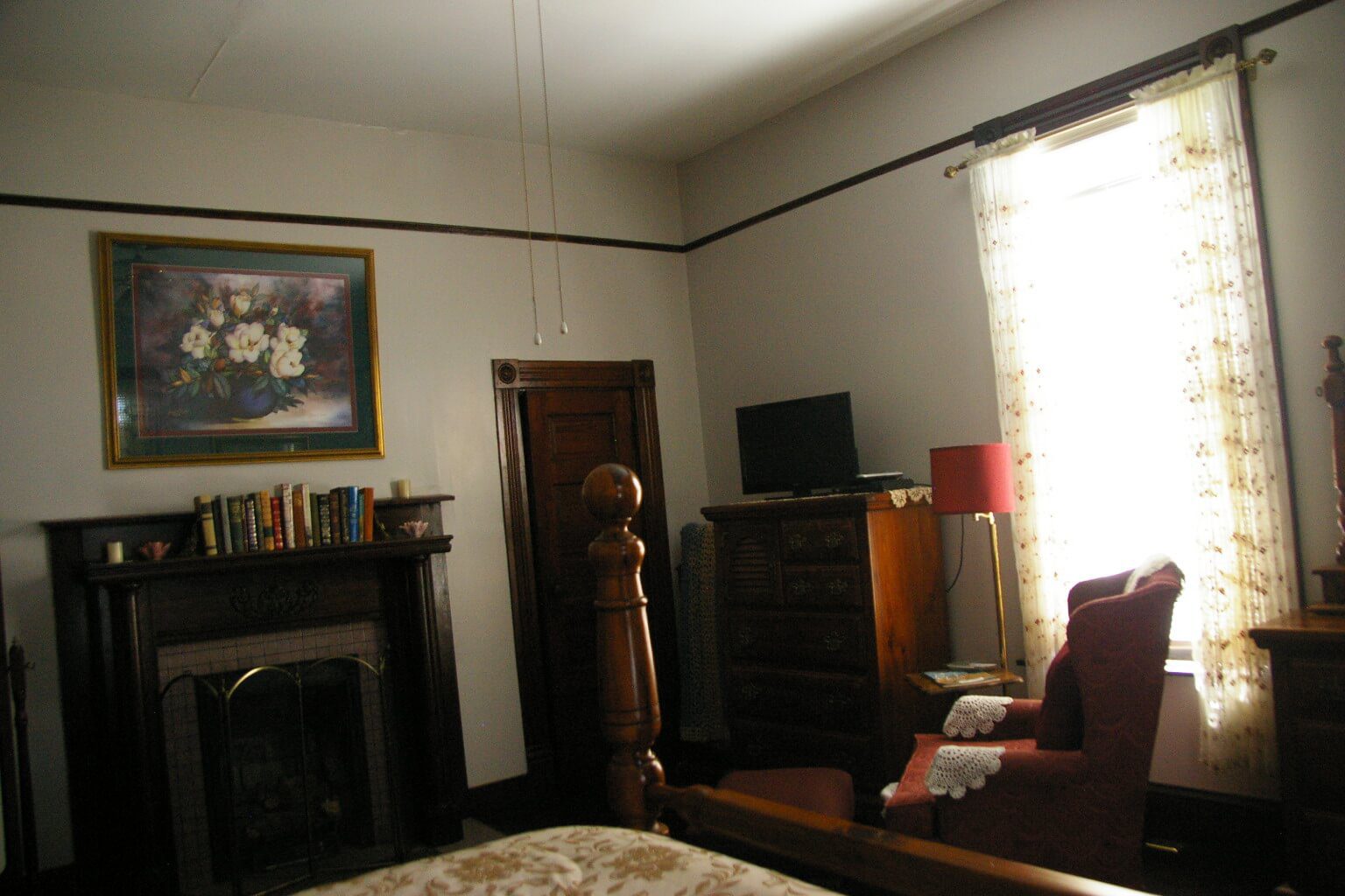 A room with a bed, fireplace and television.