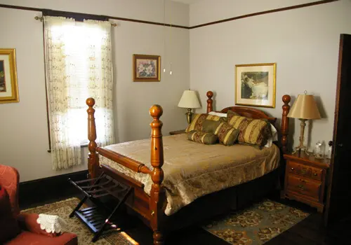 A bedroom with a bed, nightstand and chair.