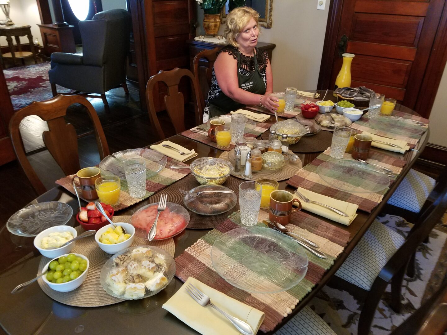 A woman sitting at the table with plates of food.